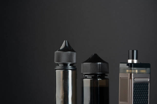 istock Vape and vape liquid bottles against black background 1637741186
