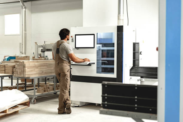 istock Young carpenter operating machine for wood processing at a furniture factory 1637756204