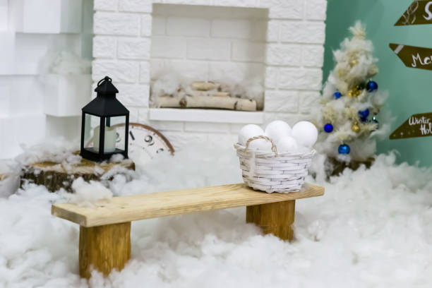 Winter New Year interior. Fireplace. lantern, bench, snow balls, Christmas tree with balls. Cozy decor in white tones in the interior of the Christmas room, a Christmas tree decorated with garlands, gifts. A festive living room in the house. New Year's h