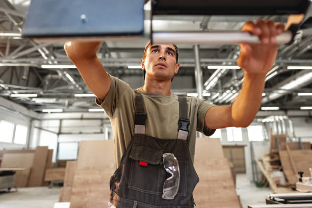 istock Young carpenter operating machine for wood processing at a furniture factory 1637767553