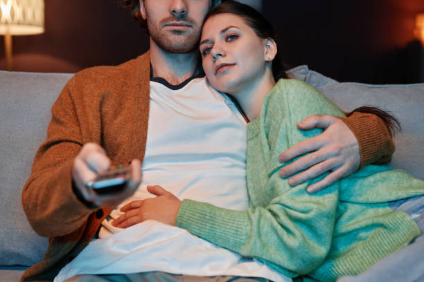 istock Young couple embracing affectionately watching TV together at home 1637842035