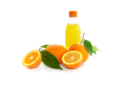 Bottle with orange drink and fresh, ripe oranges on white background close-up