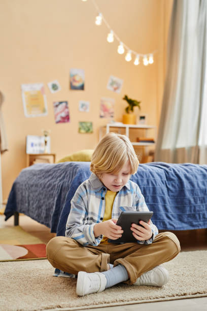 istock Cute blond boy looking at screen of table while watching online movie 1637874594