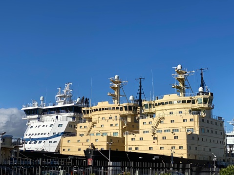Three icebreaker ships in a row next to each other in harbor in Helsinki, Finland. Sun is shining, blue sky, clouds in the horizon, late summer day, no people.