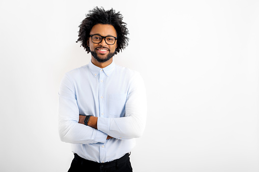 Proud pleased African-American businessman in formalwear stands with arms crossed isolated on white, small business owner, male entrepreneur in a confident pose and looking at camera, hands folded