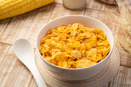Healthy crispy cornflakes in white bowl on wood table