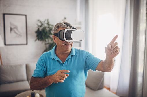 Mature man uses VR glasses at home