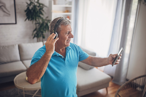 A mature man uses headphones and a mobile phone, listens to music