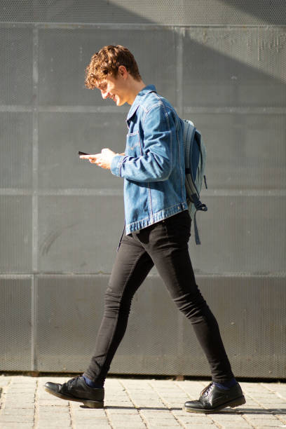istock Young man walking with mobile phone and bag on sidewalk 1637959465