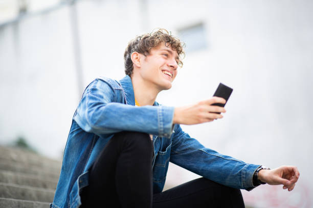 istock Young man with phone looking away and smiling outside 1637959491