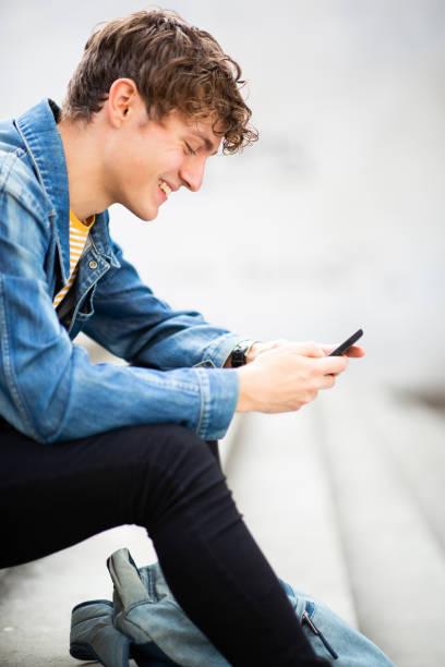 istock Handsome young man sitting outside looking at cellphone 1637959612