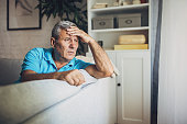 Depressed elderly man, sitting alone at home