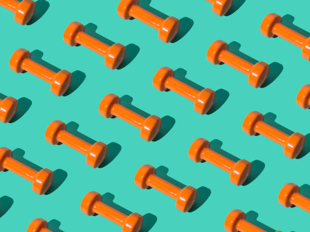 istock Creative pattern composition made of orange dumbbells on pastel green background. Minimal fitness, healthy lifestyle and sport concept. Trendy exercise and fitness backround idea. 1637984220