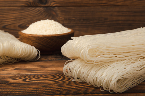 Funchoza.Dried raw rice noodles and rice on wooden background.Noodles with rice flour. Diet food. Healthy food. Place for text. Place for copying.