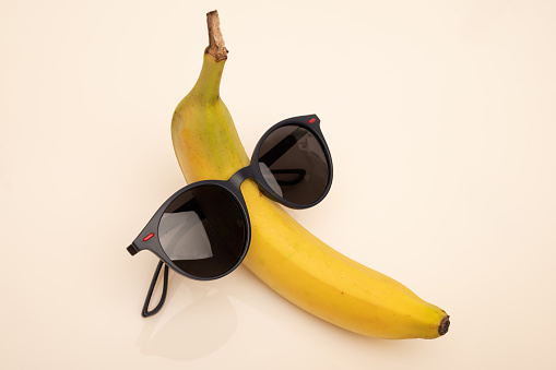 A funny banana with black sunglasses on a white background.