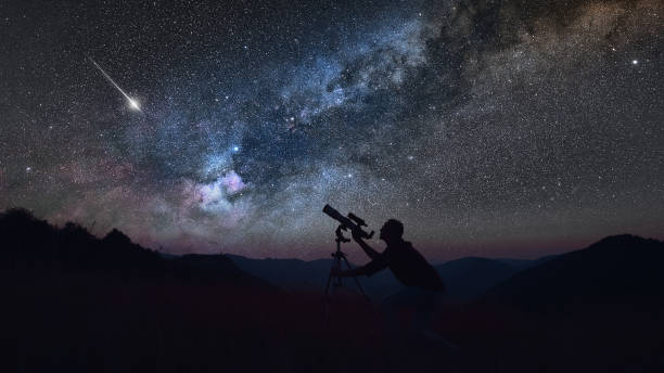Astronomer looking at the starry skies with a telescope. stock photo