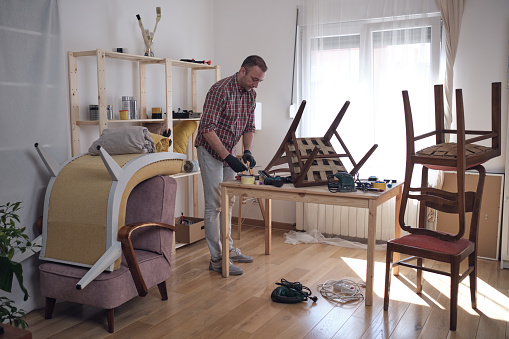 Man working in a small home workshop for furniture repairing and restoration.