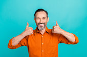 Photo of cool confident man dressed orange shirt showing two thumbs up isolated turquoise color background
