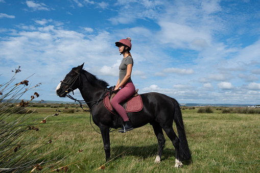 A young woman rides a horse through the countryside, Devon UK