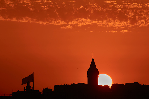 sun setting down in istanbul silhouette, showing Galata Tower and a huge Turkish Flag