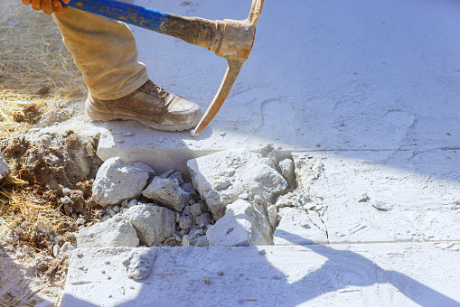 Construction site worker pickaxe demolishes concrete old driveway