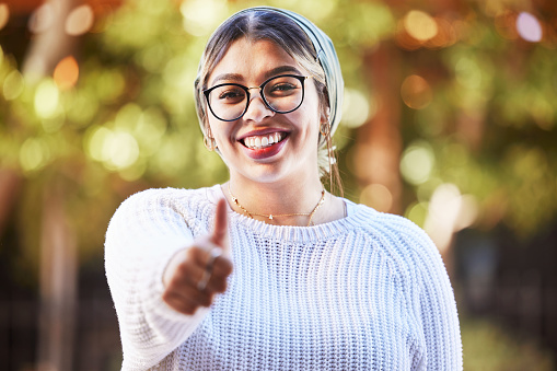 Young woman, thumbs up in portrait and smile, agreement and yes emoji with like sign and happiness. Deal, support and positive feedback, female person with review and good luck, opinion and vote
