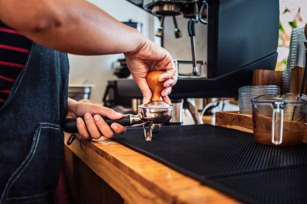 istock Hand of Barista cafe making coffee with manual presses ground coffee using a tamper making an espresso coffee on the wooden counter bar at the coffee shop 1638109790