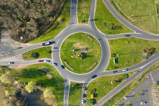 Aerial view of road roundabout intersection with moving heavy traffic. Urban circular transportation crossroads.
