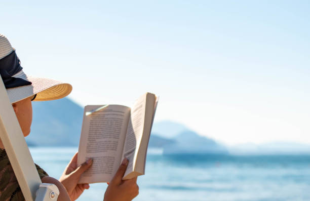 istock A girl reading next to the sea. 1638123198