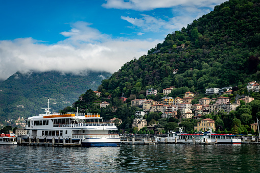 Houses on the hills surrounding Como in Italy.  This is viewed from the harbour looking North towards Cernobbio.  In the foreground are ferries and pleasure craft in Como harbour.