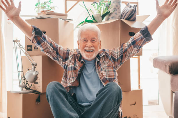 istock Happy senior man involved in moving house resting with open arms between cardboard boxes, concept of relocation, retirement, new life, buying, renting, apartment, house 1638172553