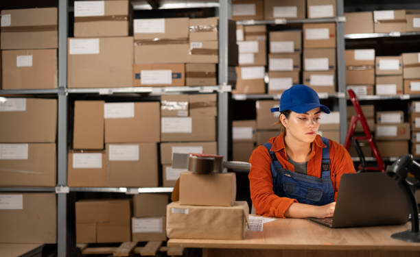 istock Young female worker working with laptop computer in storage warehouse. People, warehouse and industry concept 1638276564