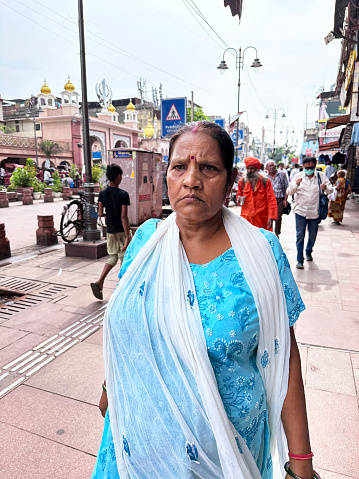 Delhi, India - July 26, 2023: Stock  photo showing close-up view of a woman walking through a retail area pasta Hindu temple.