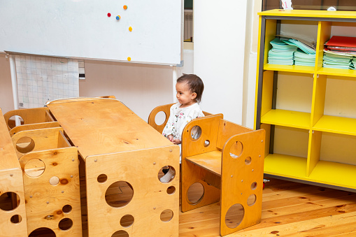 Closeup of toddler girl sitting on solid wooden montessori chair