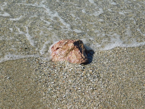 A red stone on a sandy beach, in Attica, Greece