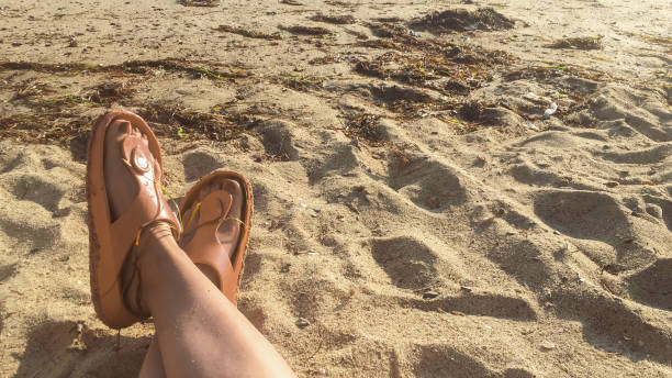 istock feet of a lady while sitting on sand at beach in summer time 1638366363