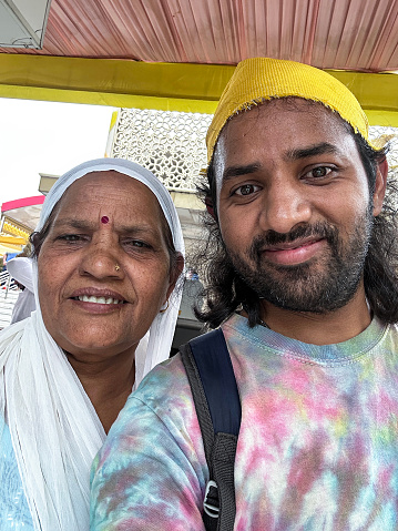 Stock photo showing close-up view of an Indian women standing outside a Hindu temple wearing a traditional sari with her son. Both are wearing head coverings in order to show gratitude, humanity and respect to the Gods.