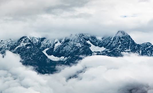 The scenery of snowy mountains amidst clouds and mist.