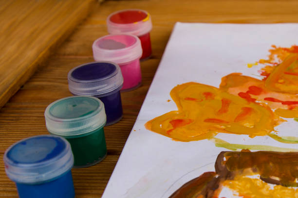 Colored gouache cans on wooden background, Paint for drawing. Kindergarten and school. Multi-colored paint. Children's creativity. Palette with oil paints and gouache. Workplace of the artist.