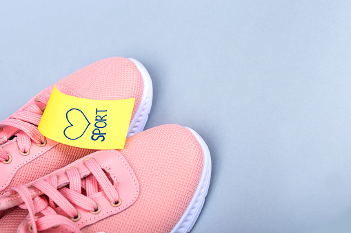 Pink women's sneakers. Text sport on sneakers.\nSneakers and a note. Small note on yellow paper. Love for sports