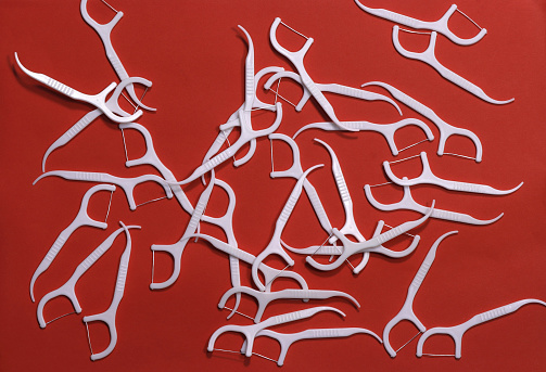 Image of white toothpicks with a thread on a red background.