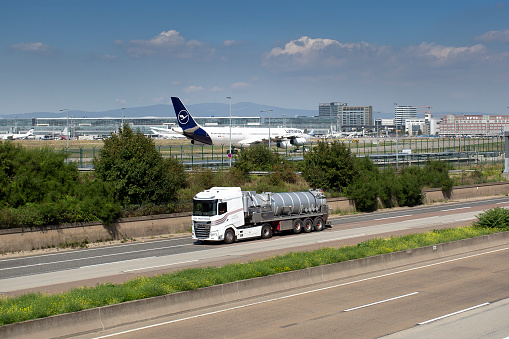 Frankfurt, Germany - August 23, 2023: A taxiing airplane of German airline Lufthansa at Frankfurt International airport. German highway A5 and a passing truck in the foreground