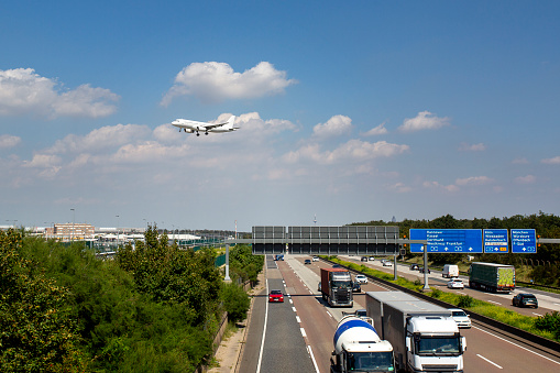 Frankfurt, Germany - August 10, 2023: A landing airplane at Frankfurt International airport. German highway A5 in the foreground