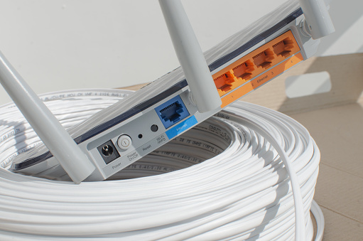 Close-up detail of a modern Wi-Fi router, with multiple inputs and ports for cable connections, representing internet technology and connections