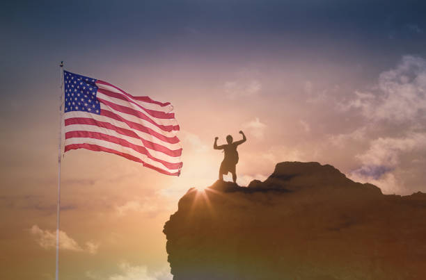 istock USA flag and victorious man on a mountain. 1638505345