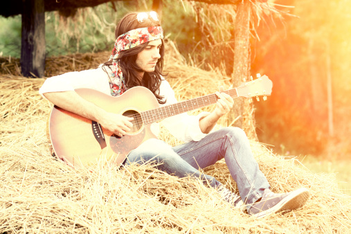 Hippie playing a guitar on hay\u2028http://www.massimomerlini.it/is/lifestyles.jpg