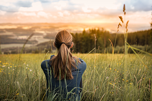 Woman sitting in the meadow enjoying beautiful view. Location Czech Republic, Europe.