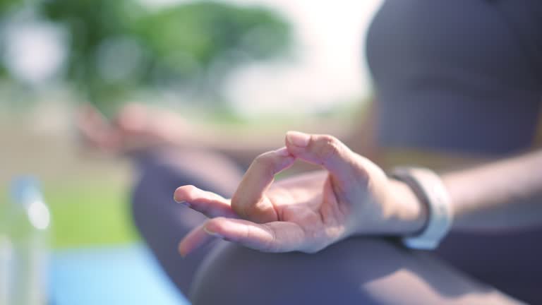 Close-up shot of female sit cross-legged on yoga mat do meditation practice at public park.