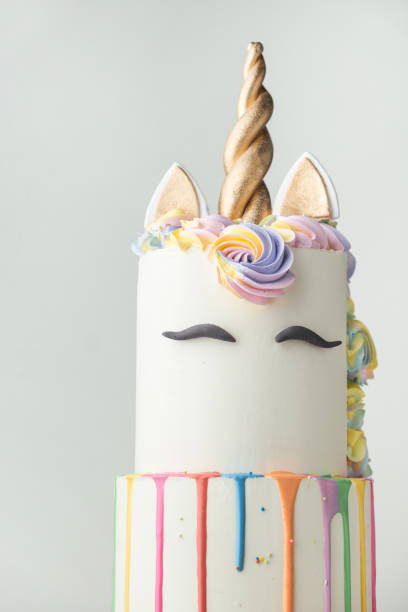 istock Big bunk cake with white chocolate frosting decorated with colorful drips, mastic eyebrows and golden ears with horn on top. Birthday party unicorn cake for a little girl on the white background. 1638539971