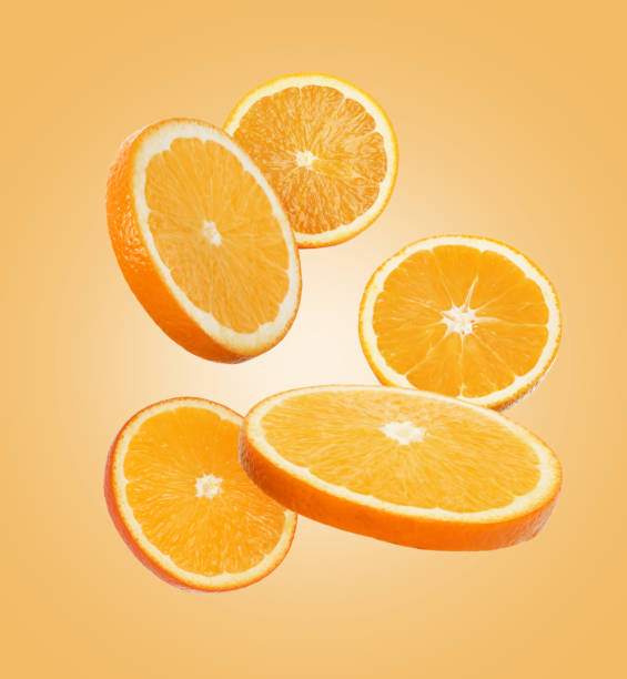 istock Juicy orange slices flying on pale orange background 1638554723